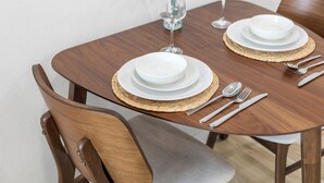 Une table à manger dressée avec de l’argenterie, des assiettes blanches et un verre d’eau.