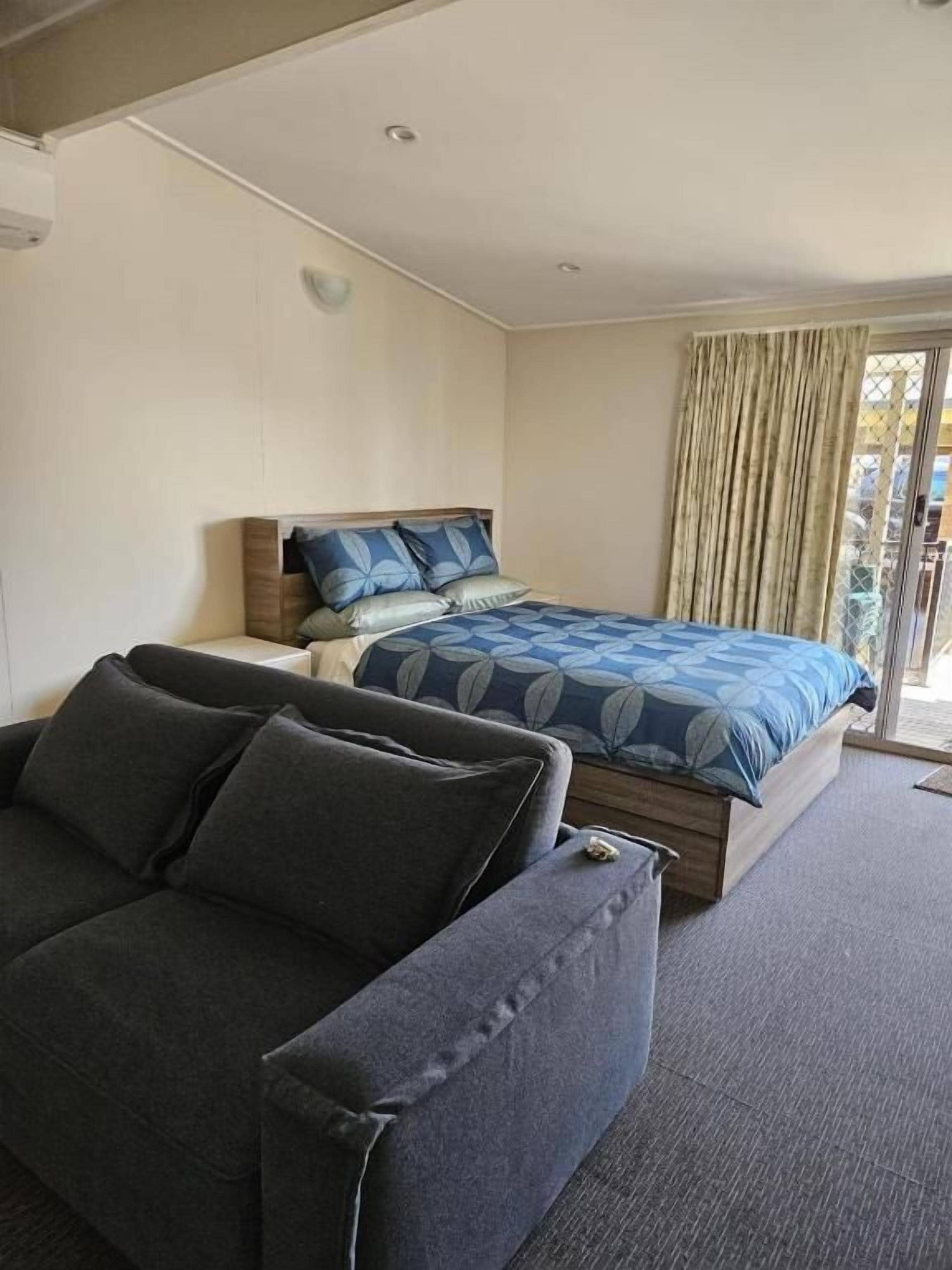 Un dormitorio con cama, sofá y ventana con cortinas.