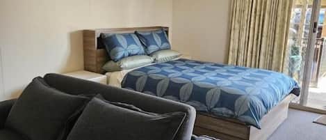 Un dormitorio con cama, sofá y ventana con cortinas.