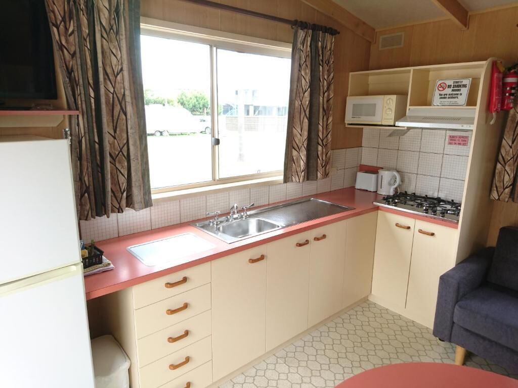 A compact kitchen with a sink, stove, microwave, and cabinets.