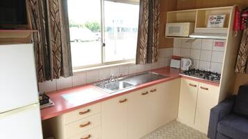 A compact kitchen with a sink, stove, microwave, and cabinets.