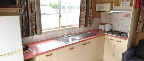 A compact kitchen with a sink, stove, microwave, and cabinets.
