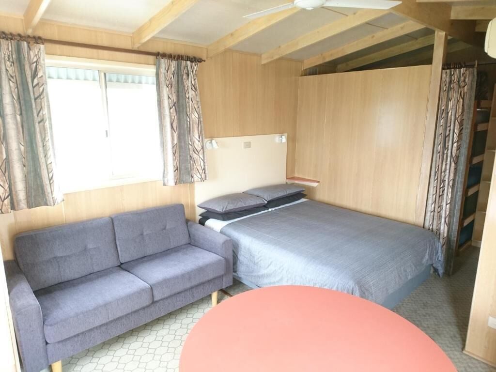 A compact room with a bed, a sofa, and a small table.
