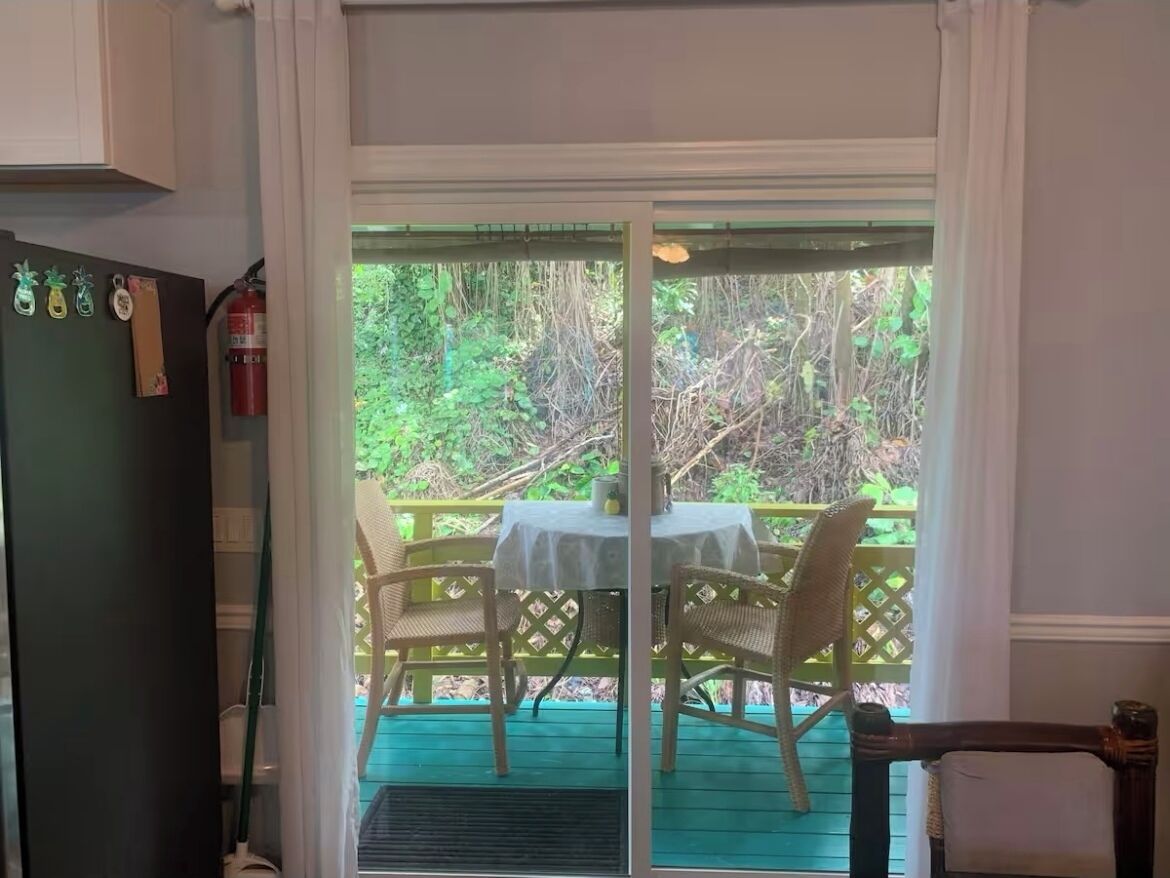 A room with a sliding glass door leading to an outdoor deck with a table and chairs.