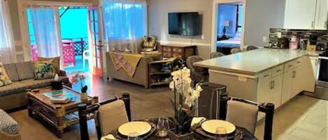 A spacious living area with a dining table set for four, a sofa, and a television in the background.