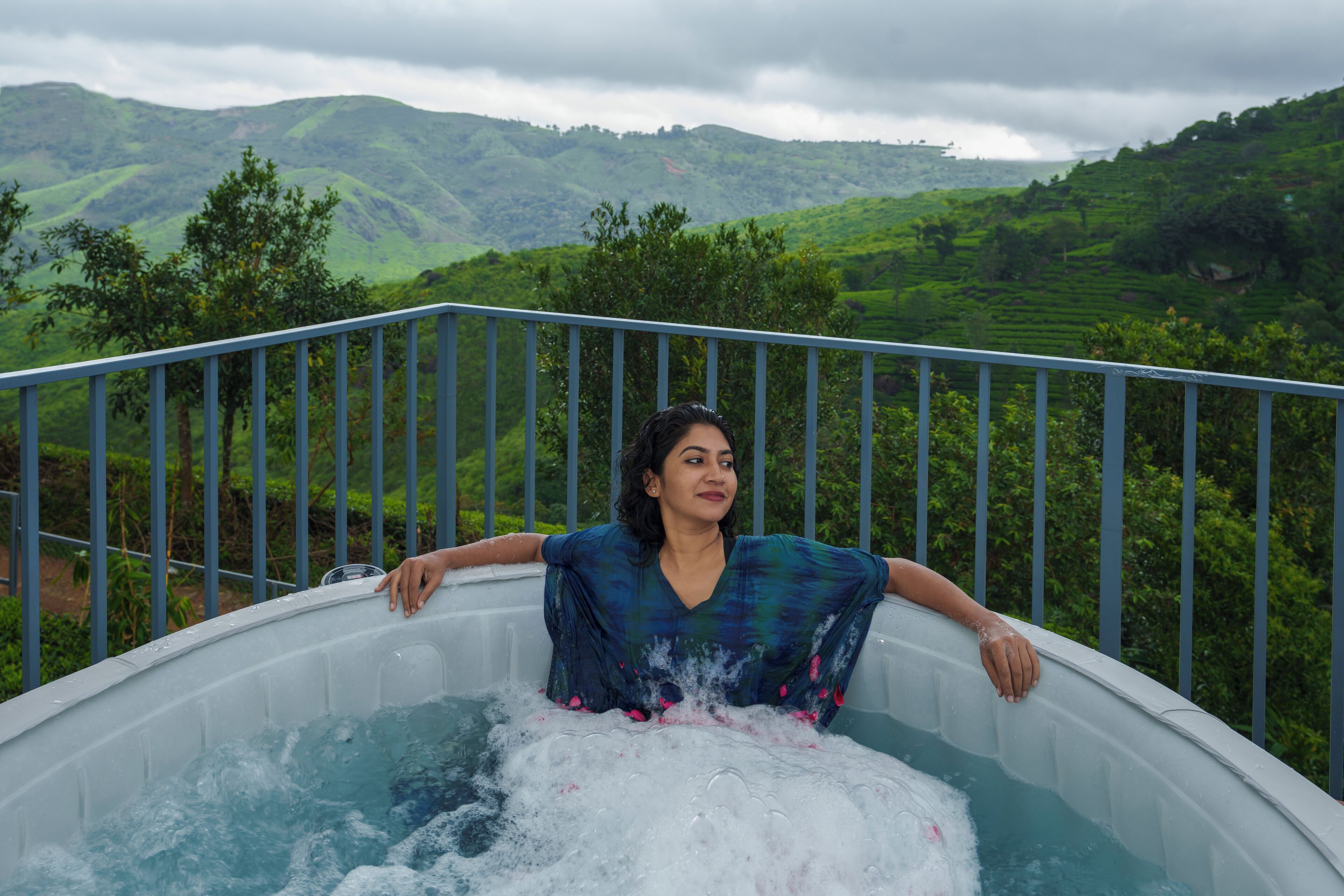 Una persona relajándose en un jacuzzi con una vista panorámica de colinas verdes al fondo.