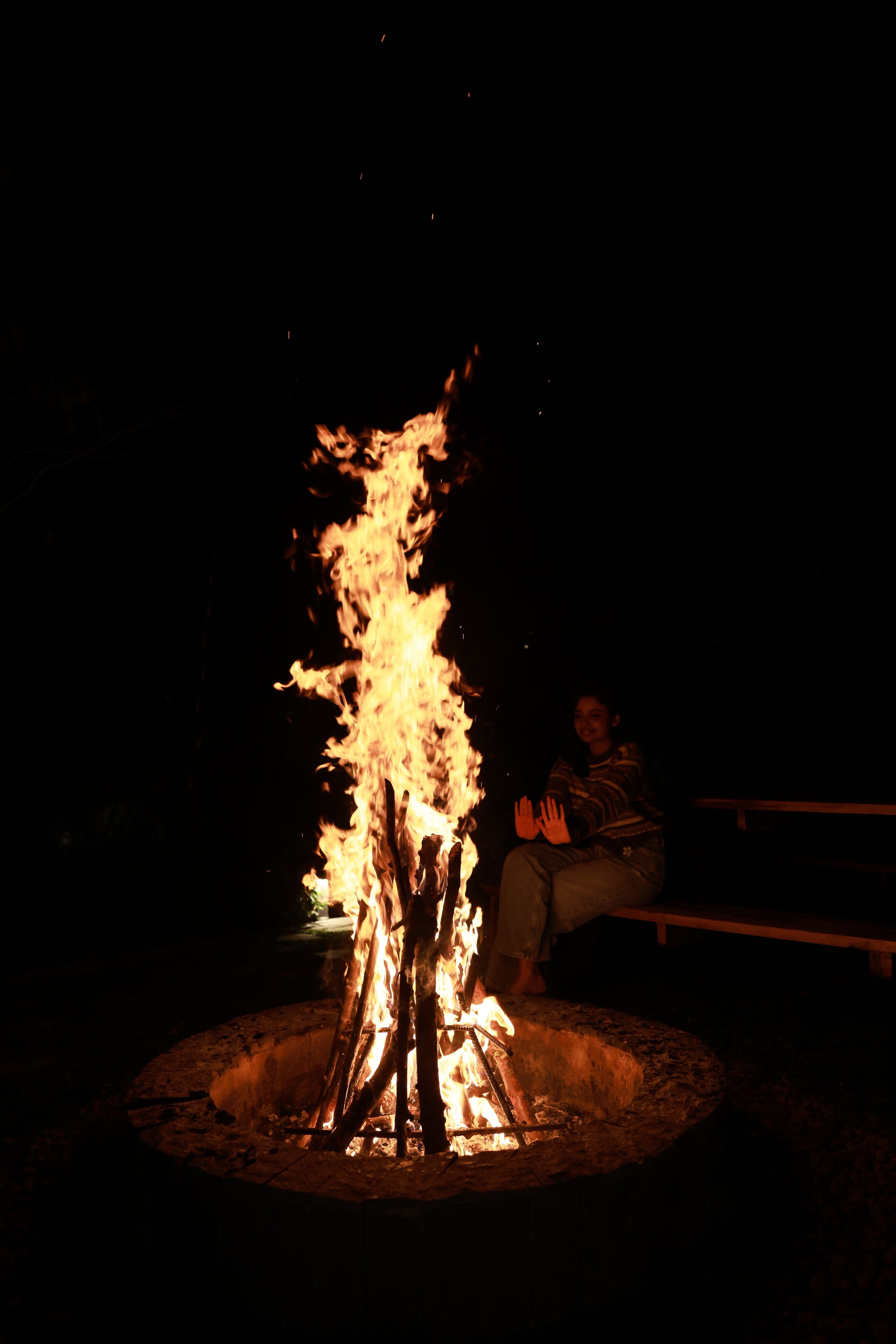 A person sitting by a campfire at night.