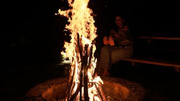 A person sitting by a campfire at night.