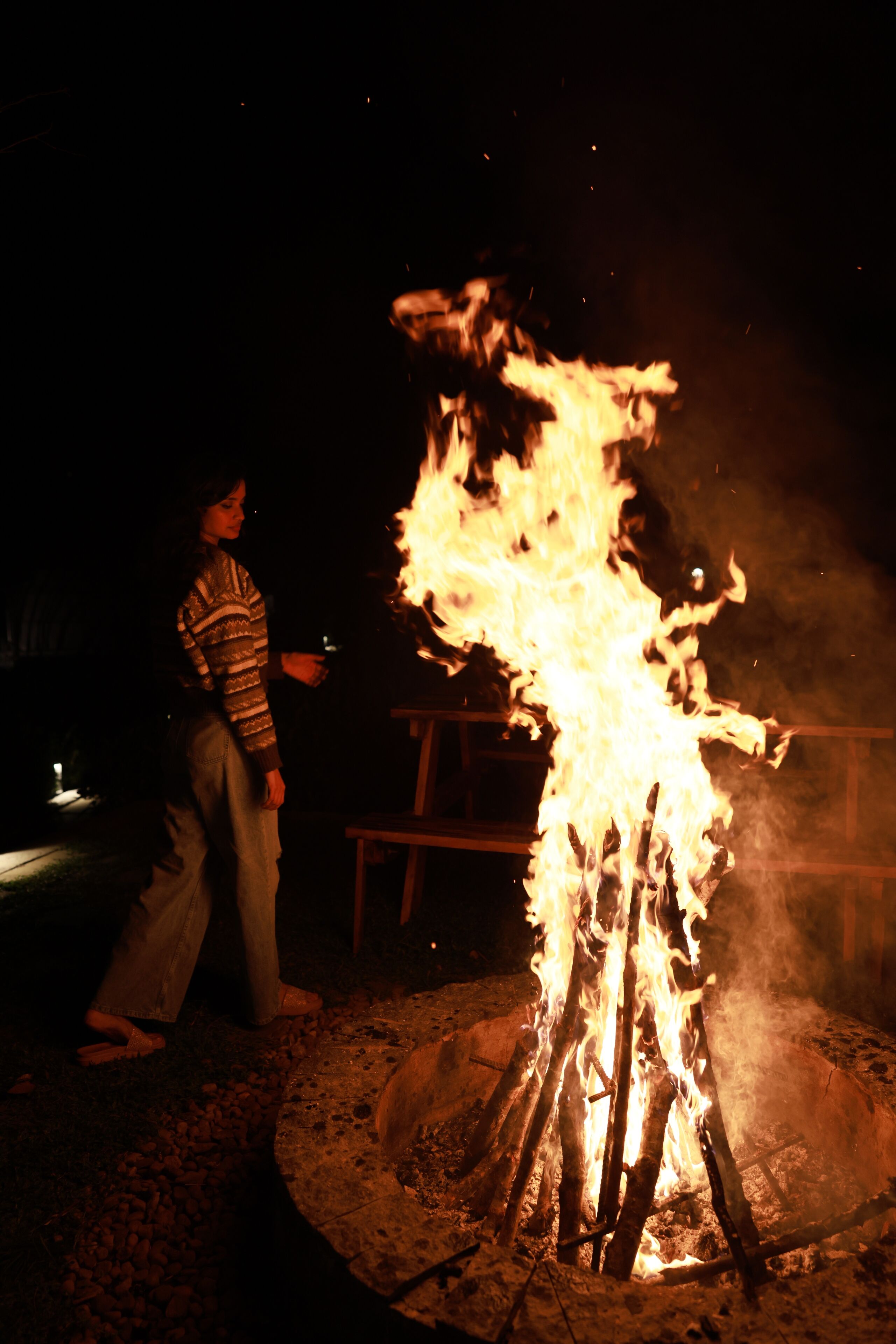 A person standing near a campfire at night.