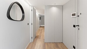 A modern hallway with a wooden floor, white walls, and a large mirror on the left. - GuestReady - Age of Discoveries - Gama (Porto)
