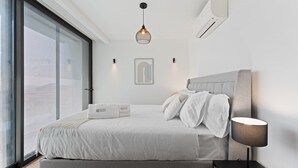 A modern bedroom with a large bed, a bedside lamp, and a view through a sliding glass door. - GuestReady - Age of Discoveries - Cabral Apt (Porto)