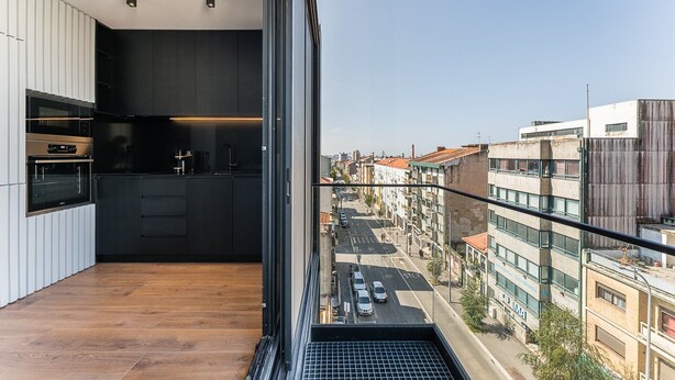 A modern apartment with a kitchen, a balcony with a city view, and a wooden floor. - GuestReady - Age of Discoveries - Cabral Apt (Porto)