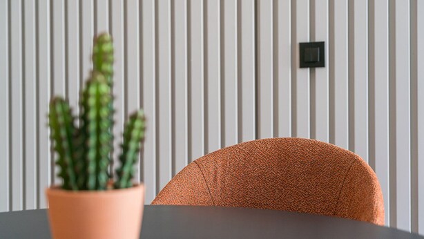 Une pièce avec un mur à rayures, une plante en pot et une chaise.