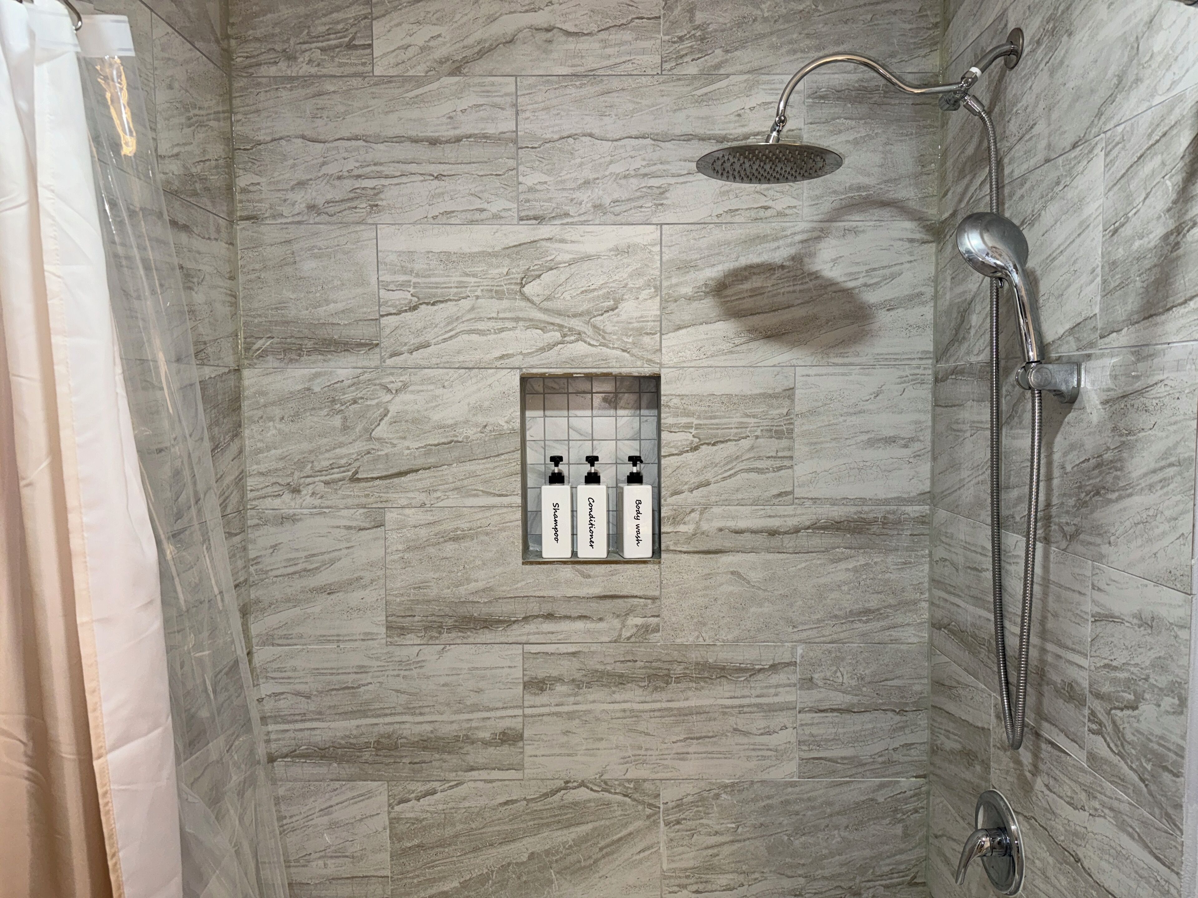 A shower area with a built-in shelf containing toiletries.
