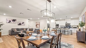 A modern living room with a dining area, kitchen, and a staircase leading to another level.