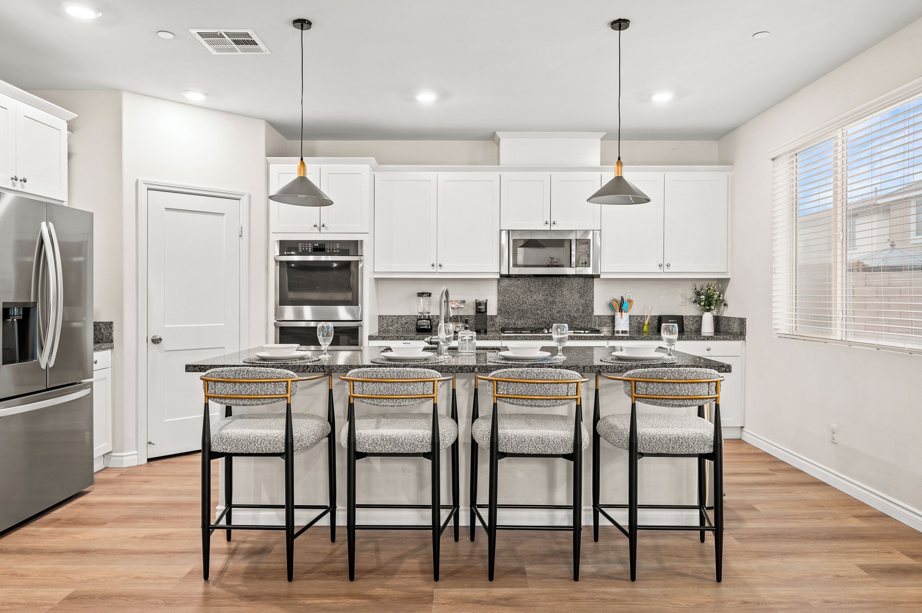 A modern kitchen with white cabinets, stainless steel appliances, and a central island with bar stools.