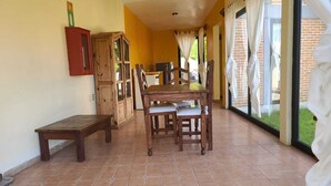 A dining area with a wooden table and chairs, a bench, and a cabinet. - Cabañas Entrada a la Sierra (Zacapoaxtla)