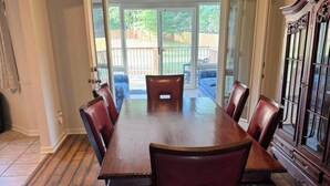 Een eetkamer met een grote houten tafel, zes stoelen en een plafondventilator.