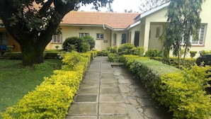 A stone pathway leading to a building with a tiled roof. - Ack Guest House Machakos (Machakos)