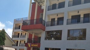 A multi-story building with a red and white facade, balconies, and a sign indicating a resort. - Ack Guest House Machakos (Machakos)