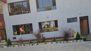A modern building with multiple windows, a red and white facade, and a paved entrance area with small plants. - Ack Guest House Machakos (Machakos)