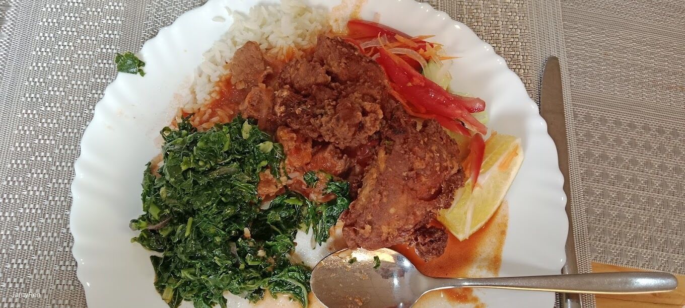 A plate with white rice, a meat dish, and greens.