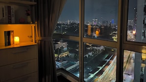 Une pièce dotée d’une grande fenêtre donnant sur une vue panoramique de la ville la nuit.