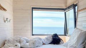 Un dormitorio con cama, ventana y vista al mar.