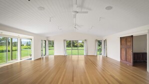 A spacious room with a high ceiling, large windows, and a wooden floor.