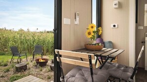 An outdoor seating area with a table, chairs, a fire pit, and a view of a field.