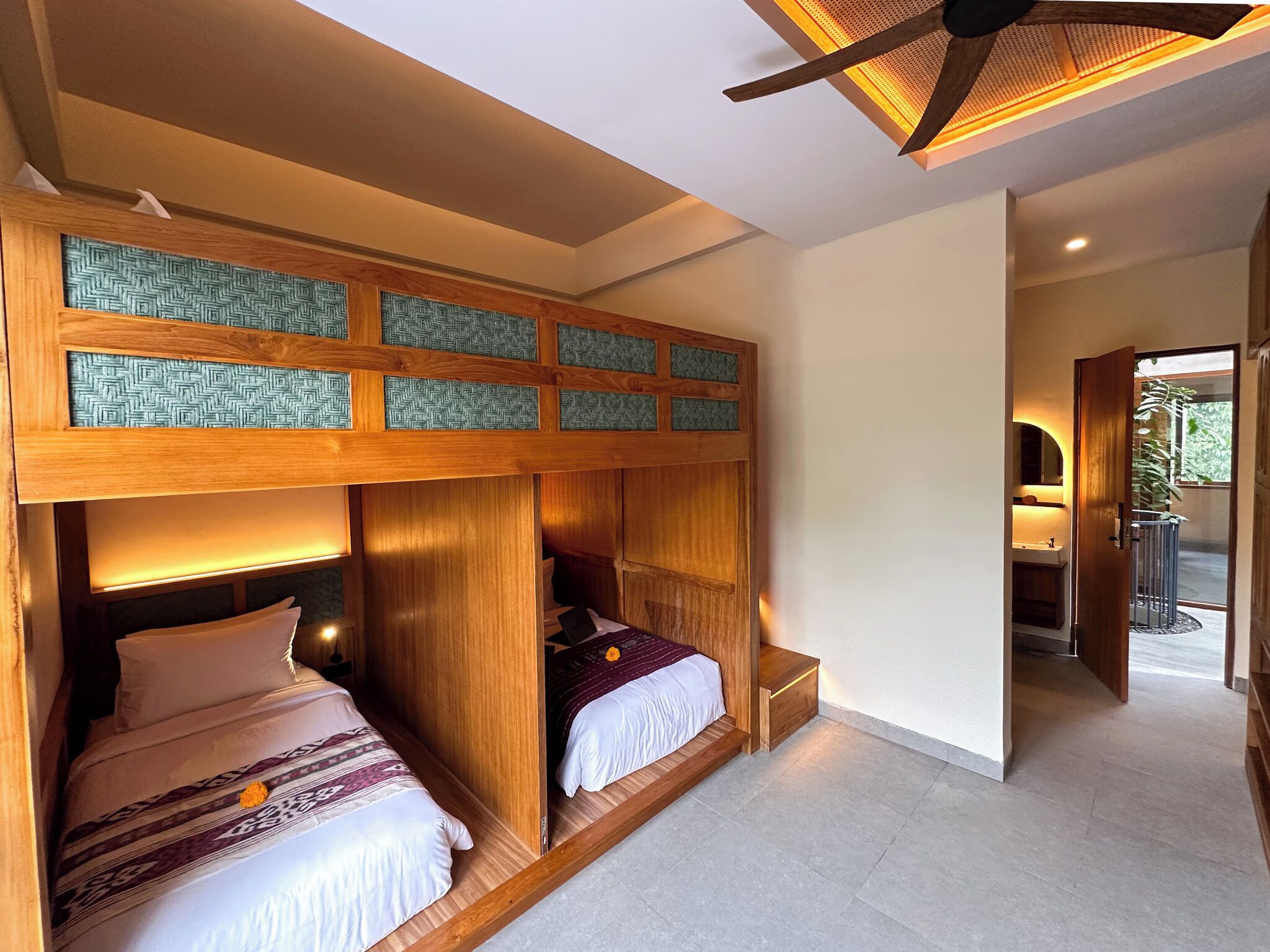 A bedroom with two beds, wooden headboards, and a ceiling fan.