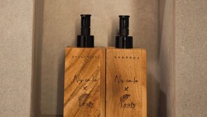 Deux flacons en plastique noir, étiquetés « Gel douche » et « Shampoing », de la marque « Leafy Riverbank ».