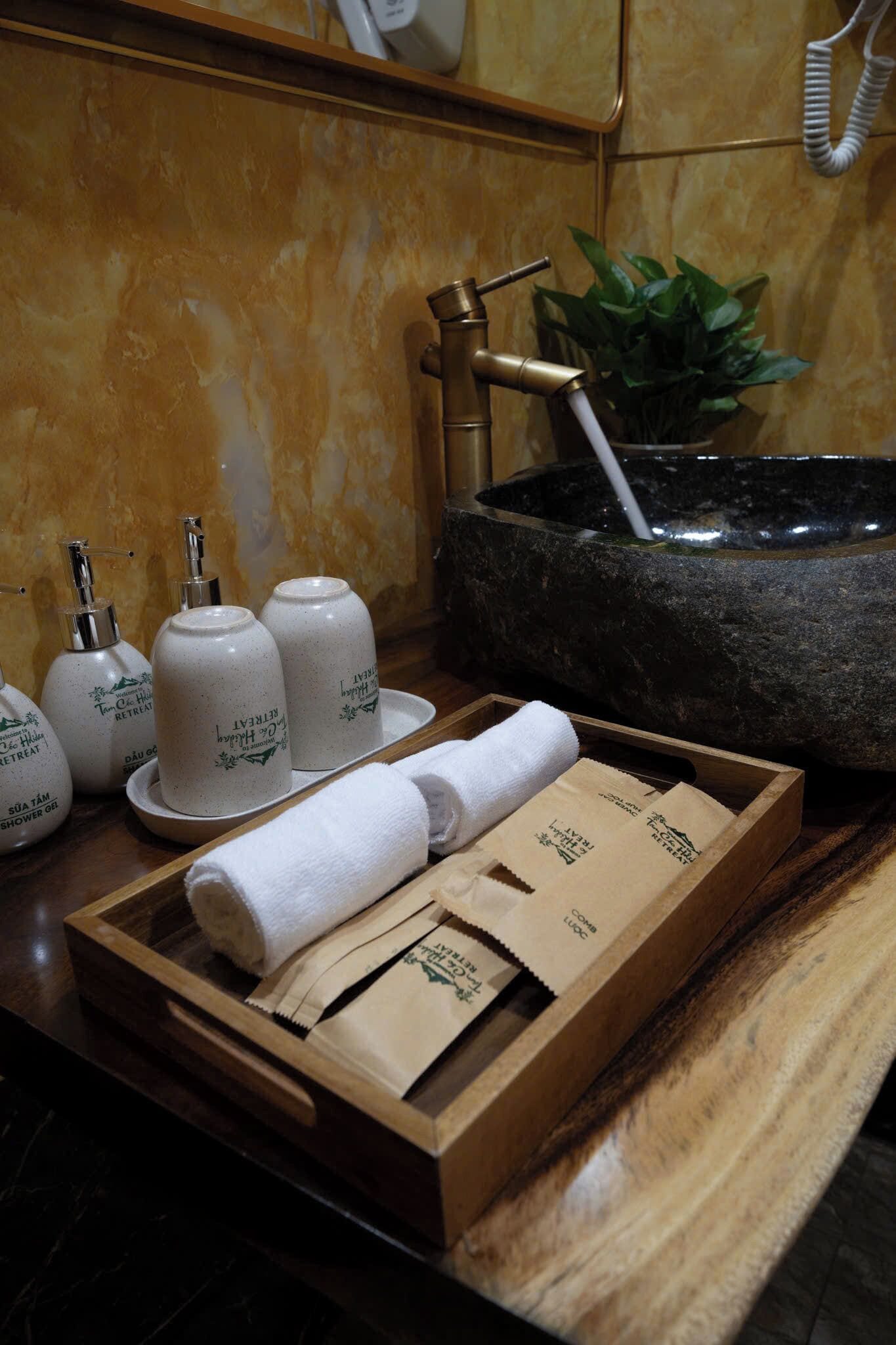 A wooden tray with towels and toiletries on a bathroom counter.