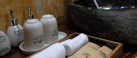 A wooden tray with towels and toiletries on a bathroom counter.