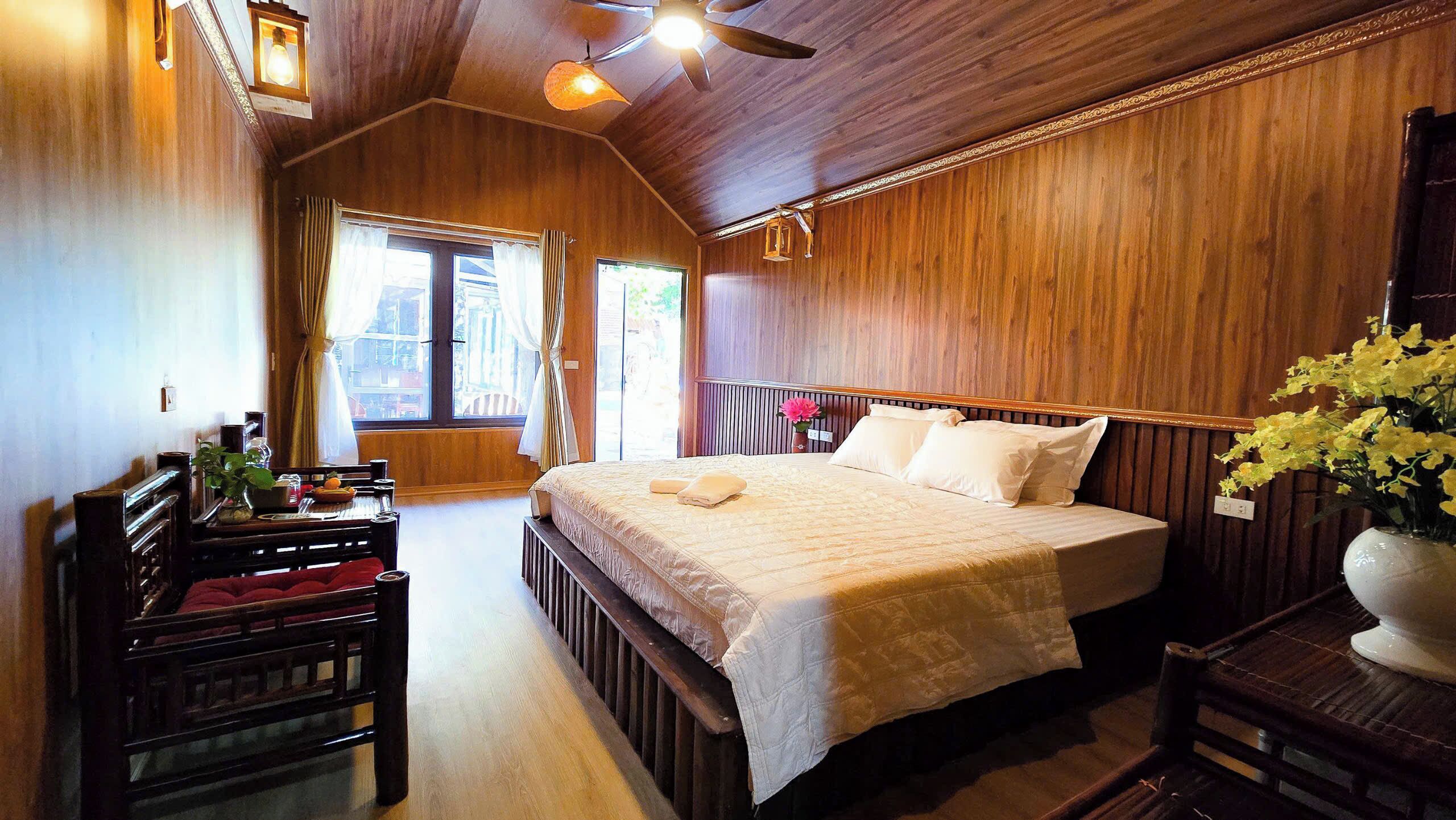 Un dormitorio con paneles de madera, una cama grande, un escritorio de madera y una silla.