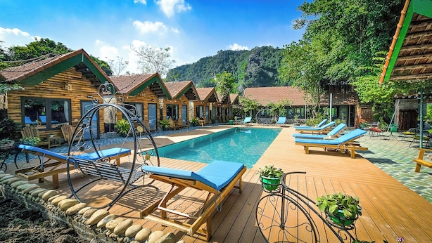 A pool area with wooden deck, lounge chairs, and a clear view of the surrounding forest. - Tam Coc Holiday Retreat (Nam Hoa Lu)