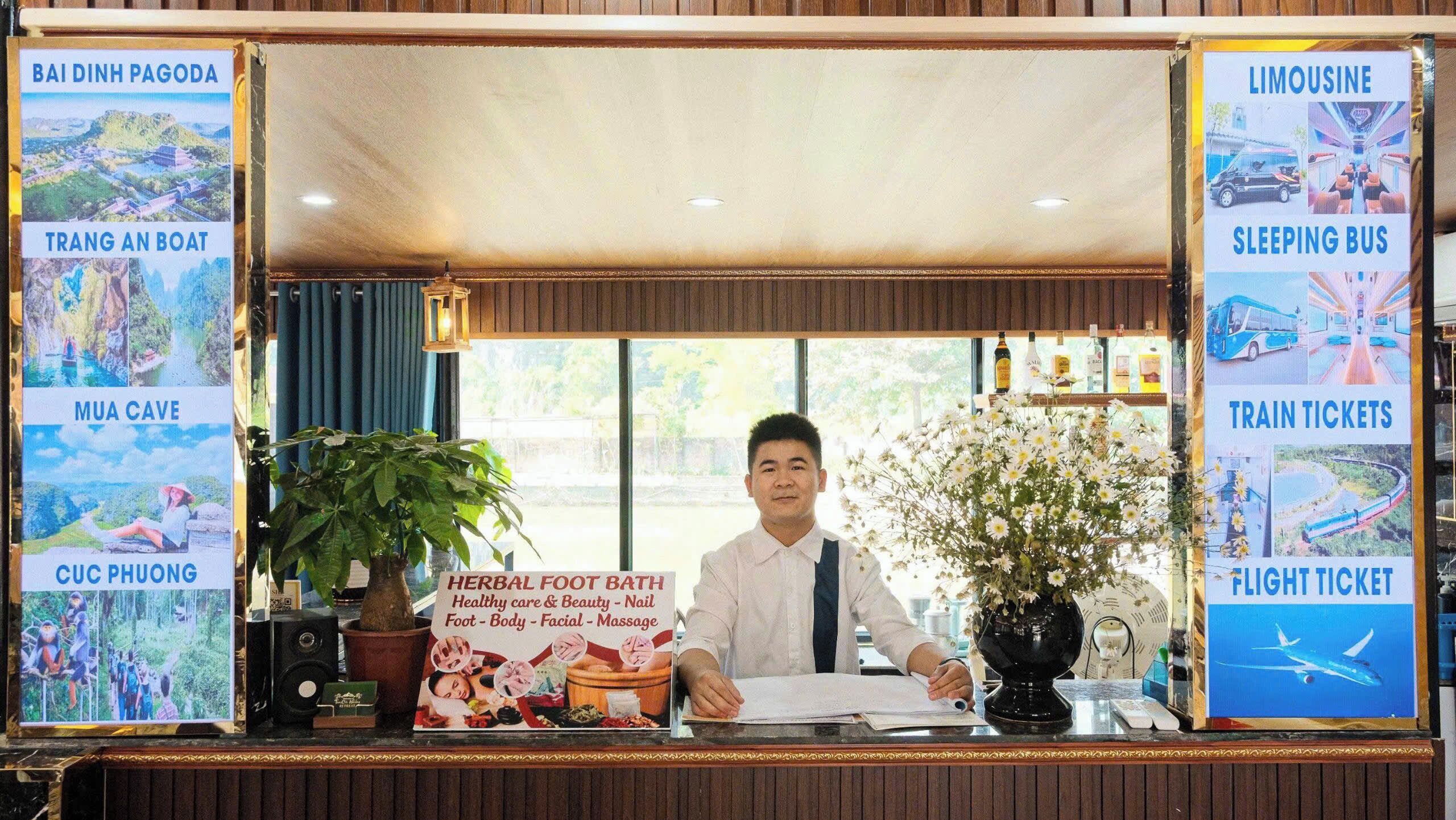 A reception desk with a sign for a herbal foot bath, a potted plant, and a poster advertising a sleeping bus.
