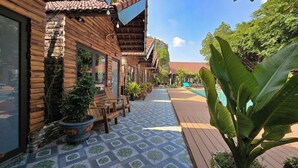 A wooden building with a tiled patio and a pool area. - Tam Coc Holiday Retreat (Nam Hoa Lu)