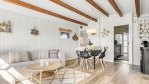 A spacious living room with a sofa, coffee table, and dining area with chairs.
