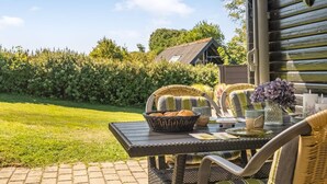 An outdoor patio with wicker furniture, a table set with bread, a basket, and a vase of flowers.