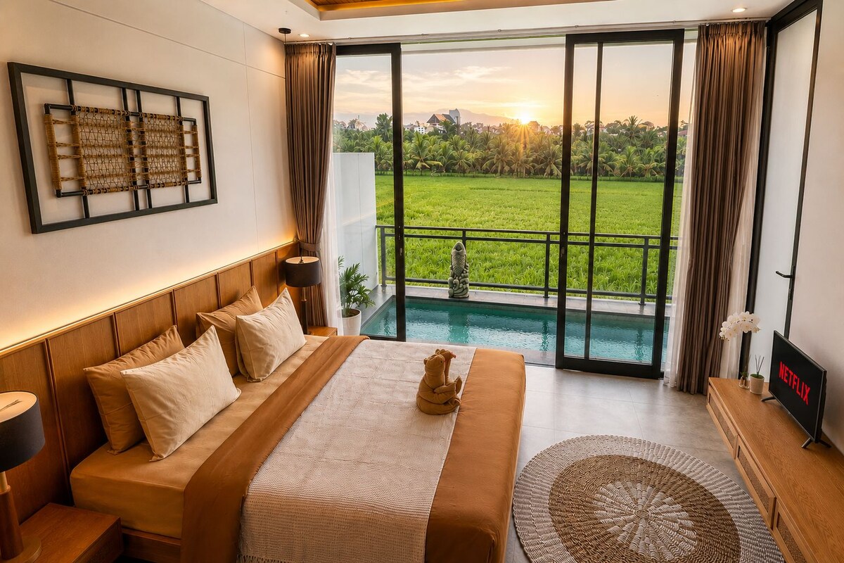 A bedroom with a large bed, a TV, and a view of a swimming pool and greenery.