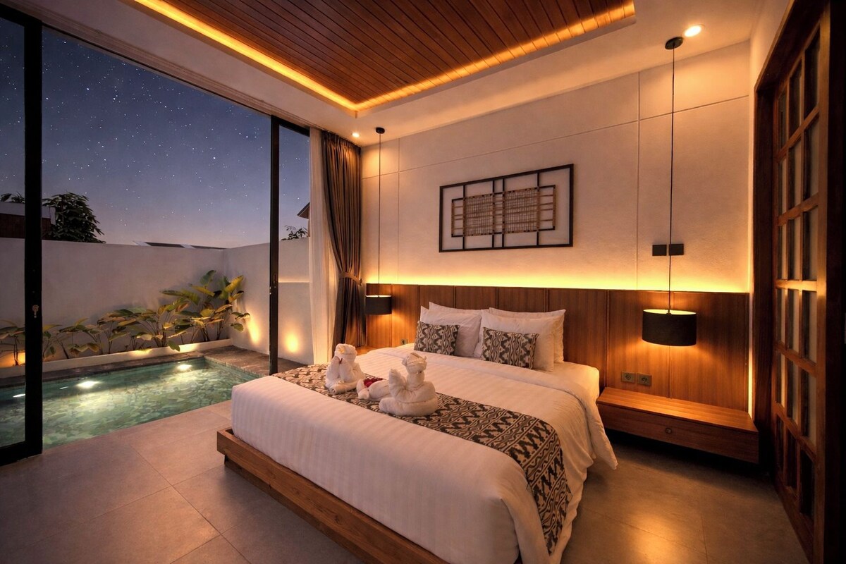 A modern bedroom with a large bed, a night sky view, a pool, and a wooden ceiling.