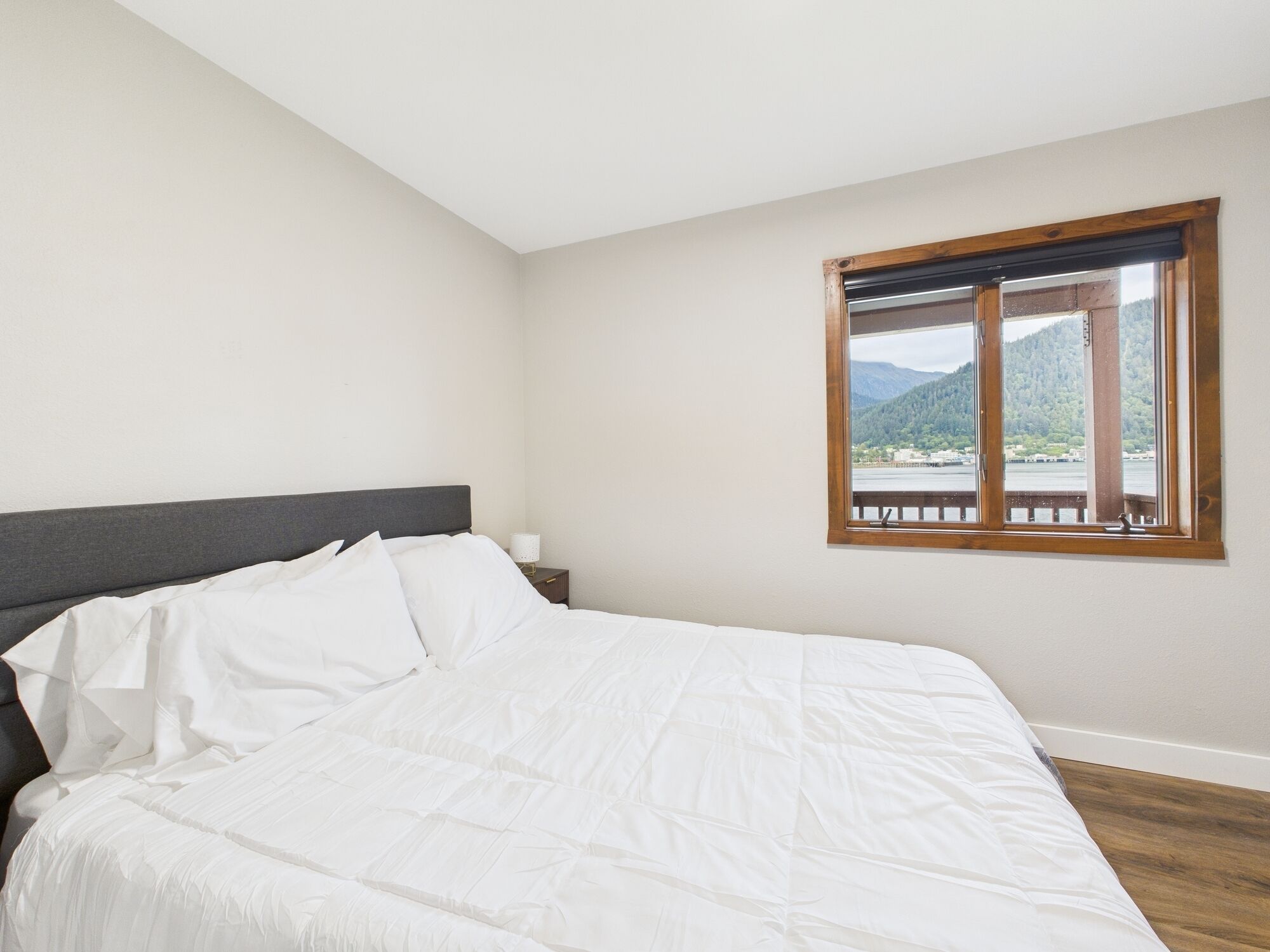 Una camera da letto con un letto, un comodino e una finestra vista lago e montagne.