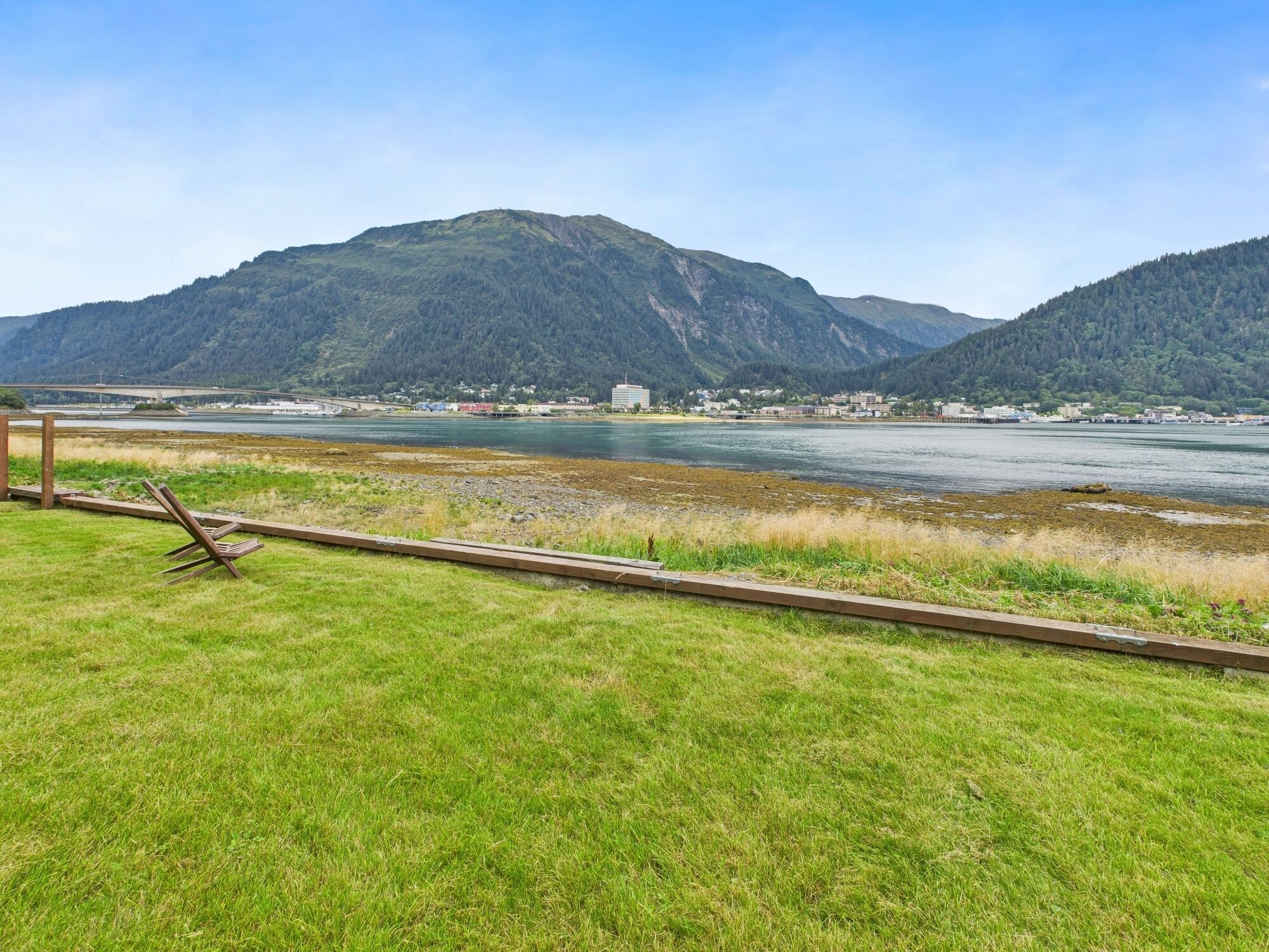 A grassy area with a wooden bench and a railway track.
