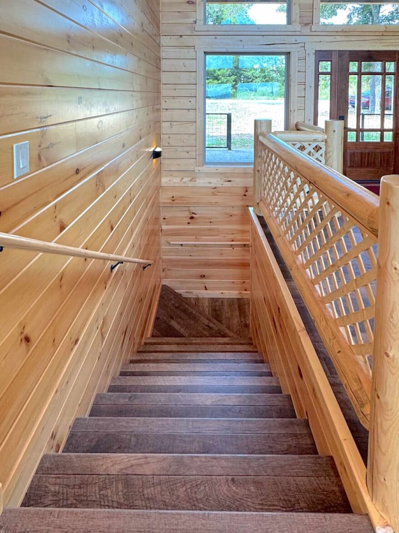 A wooden staircase with a handrail and a lattice railing on the right side.