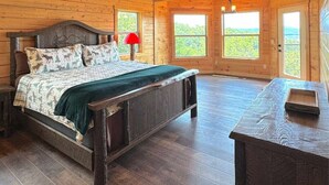 Un dormitorio de cabaña de madera con una cama, una mesita de noche, un escritorio y un ventilador de techo.