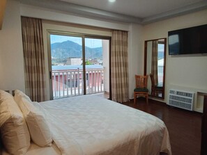 A hotel room with a large bed, a chair, a TV mounted on the wall, and a balcony with curtains. - Hotel Uttsa Inn Tamazula (Tamazula de Gordiano)