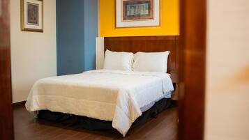 Una habitación de hotel con una cama, cabecera de madera y dos cuadros en la pared.