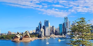 A city skyline with modern skyscrapers, a harbor with boats, and a distinctive opera house.