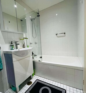 A modern bathroom with a glass-enclosed shower, a white sink, and a bathtub.
